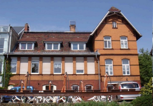Haus AWO Am See, Blick vom See Richtung Haus, rotes Backsteinhaus mit großem Erker
