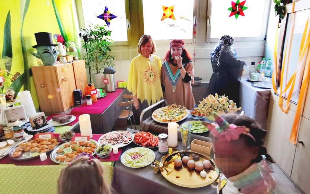 Fasching im Familienzentrum Fennpfuhl, 2 Erwachsene im Kostüm am bunten Büffet