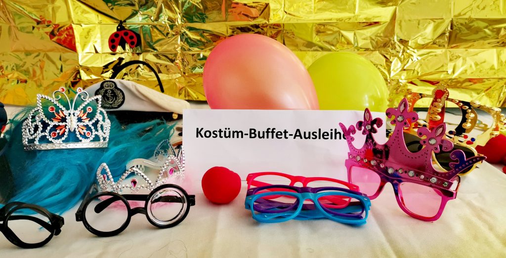 Fasching im Familienzentrum Fennpfuhl, Tisch mit Kostümteilen wie Brillen und Kronen zum Ausleihen