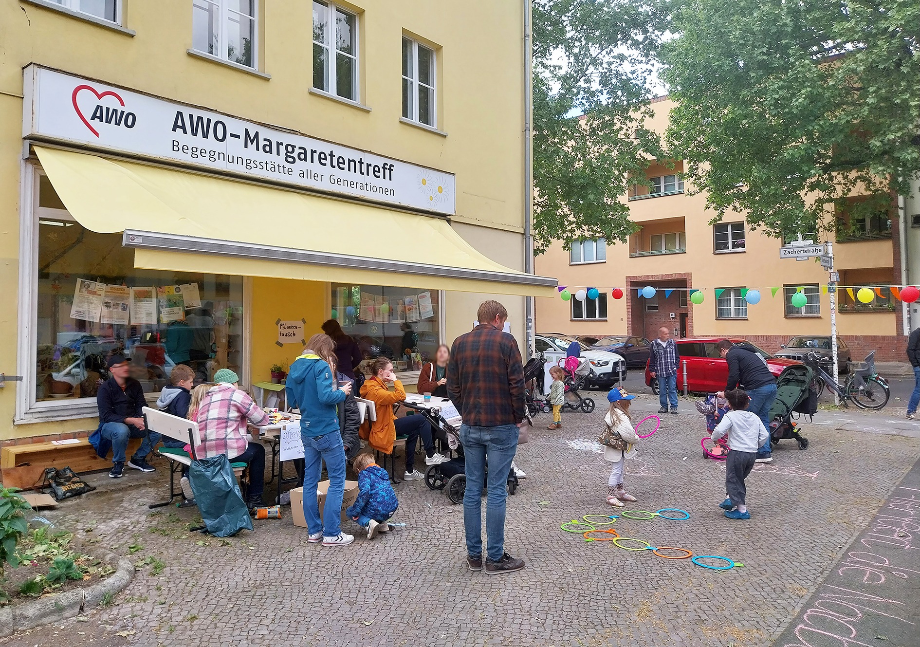 Margartetentreff, Menschen vor dem Laden treffen sich und kinder malen mit Kreide auf der Straße