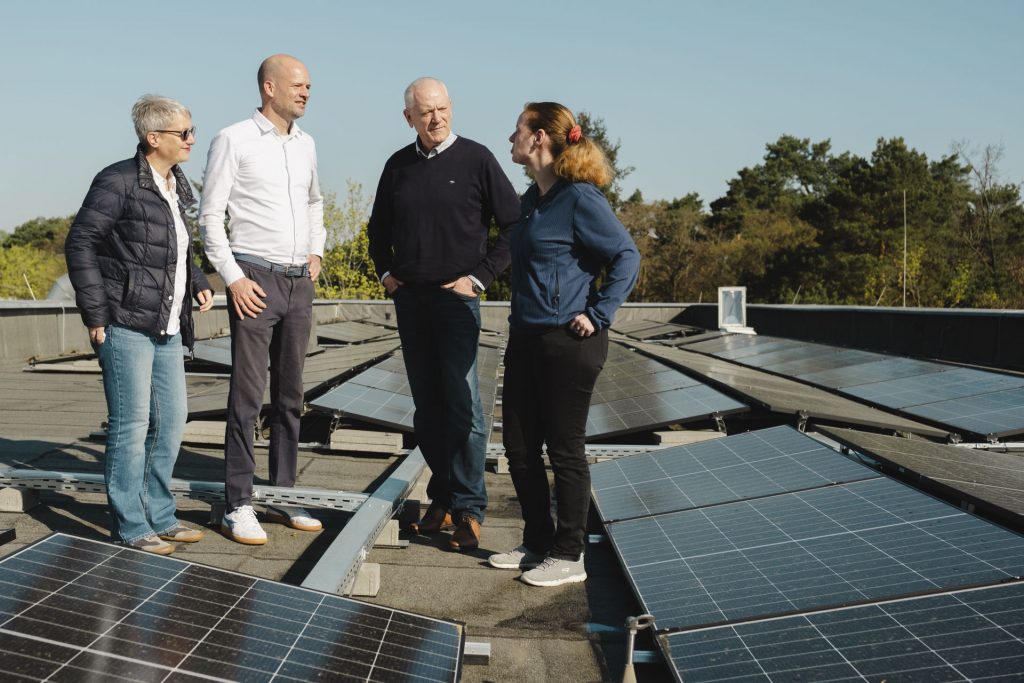 Übergabe der Solarflächen auf der Kita, Menschen stehen zwischen den Solarplattenund reden miteinander