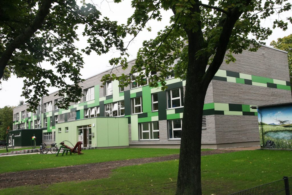Kita Grashuepfer Haus im Gruenen mit Grashüpfer aus Holz vor dem Gebaeude