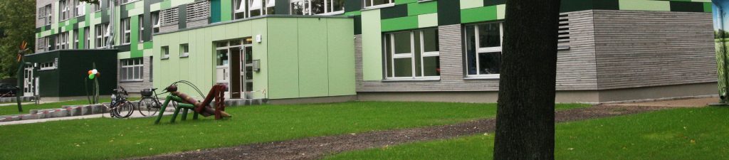 Kita Grashuepfer Haus im Gruenen mit Grashüpfer aus Holz vor dem Gebaeude