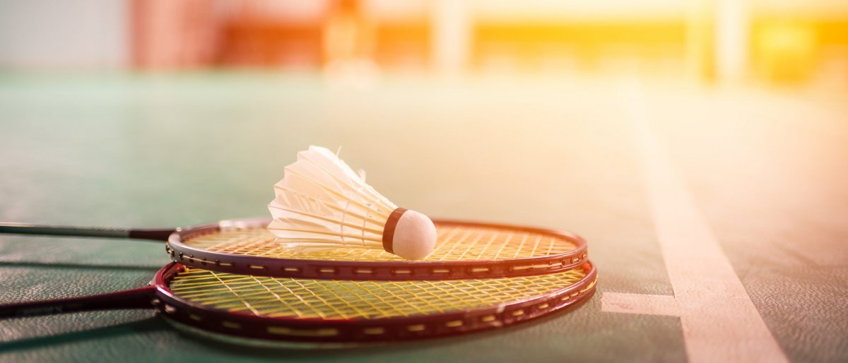 Foto: AdobeStock_202844434_©FocusStocker_Badminton ball (shuttlecock) and racket on court floor